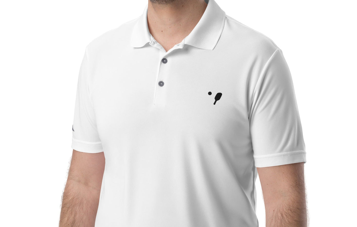 Close-up of a man wearing a white adidas® Men's Pickleball Performance Polo Shirt, focusing on the embroidered OOKAMI SPORTS pickleball logo on the left chest