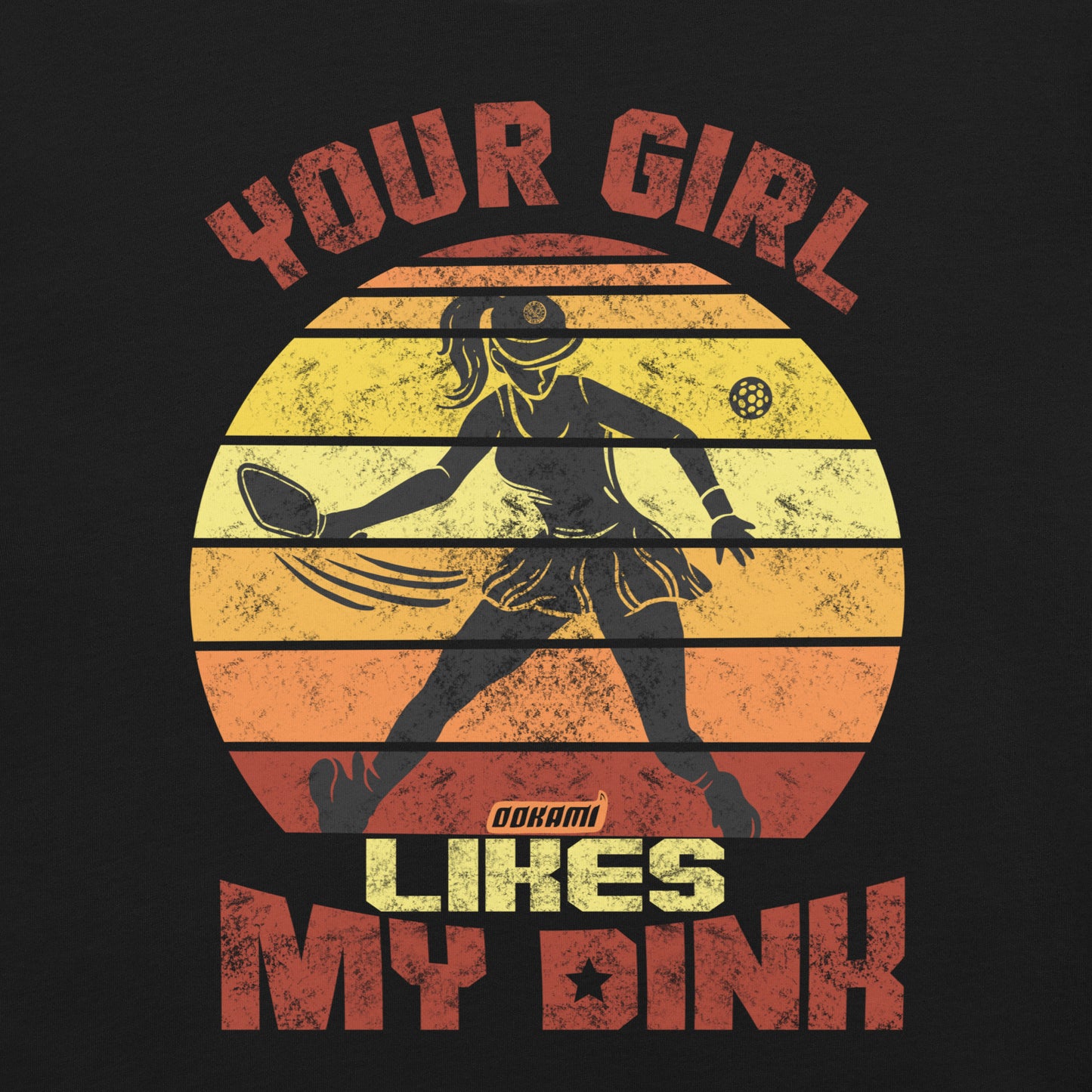 Front view of a black unisex t-shirt from Ookami Sports featuring a fun pickleball graphic. The design includes a retro sunset with a silhouette of a player holding a paddle and the text 'Your Girl Likes My Dink' in vintage-inspired colors. Perfect for expressing your pickleball pride on and off the court.