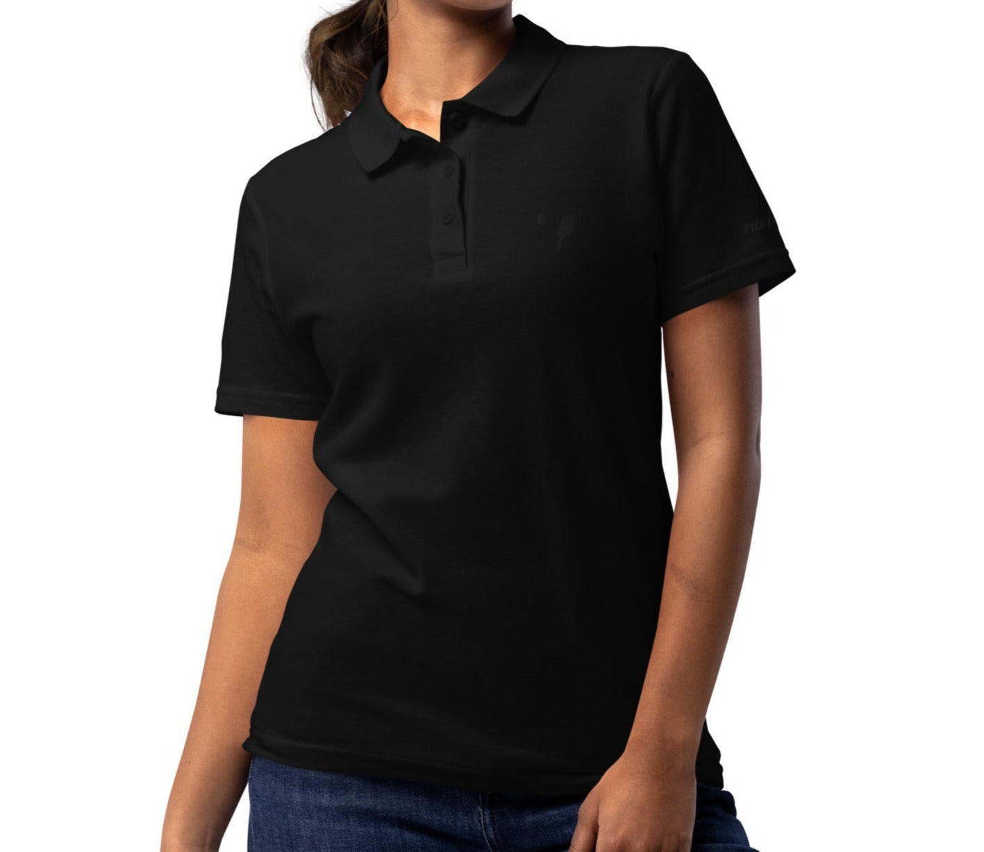 Model wearing a black women's pique polo shirt, featuring discreet black embroidery of a pickleball paddle on the left chest and logo text on the right sleeve, offered by OOKAMI SPORTS
