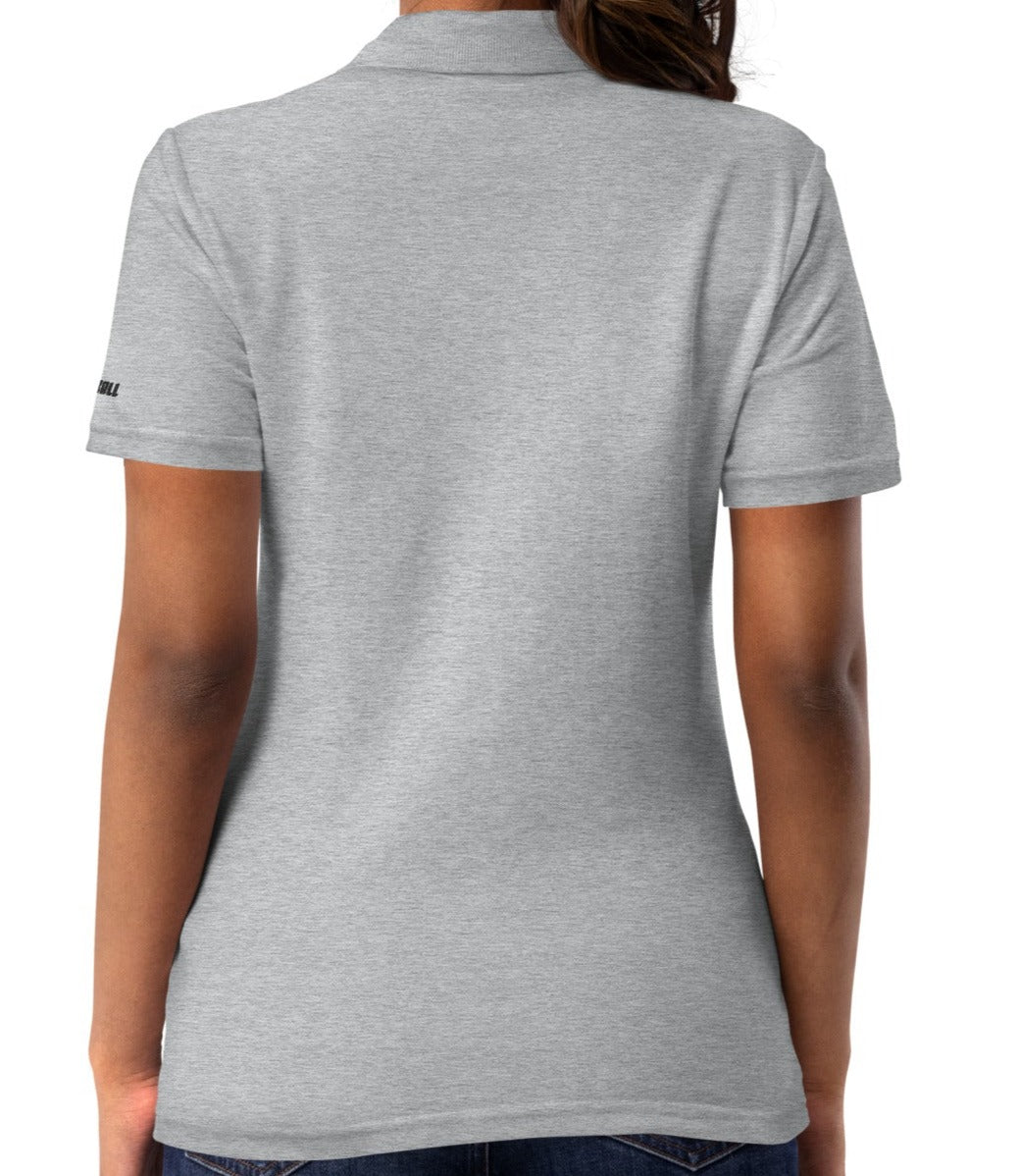 Rear view of a woman wearing a sport grey, semi-fitted OOKAMI SPORTS women's pique pickleball polo shirt, displaying a neat side-seamed construction and the brand logo subtly positioned on the right sleeve.