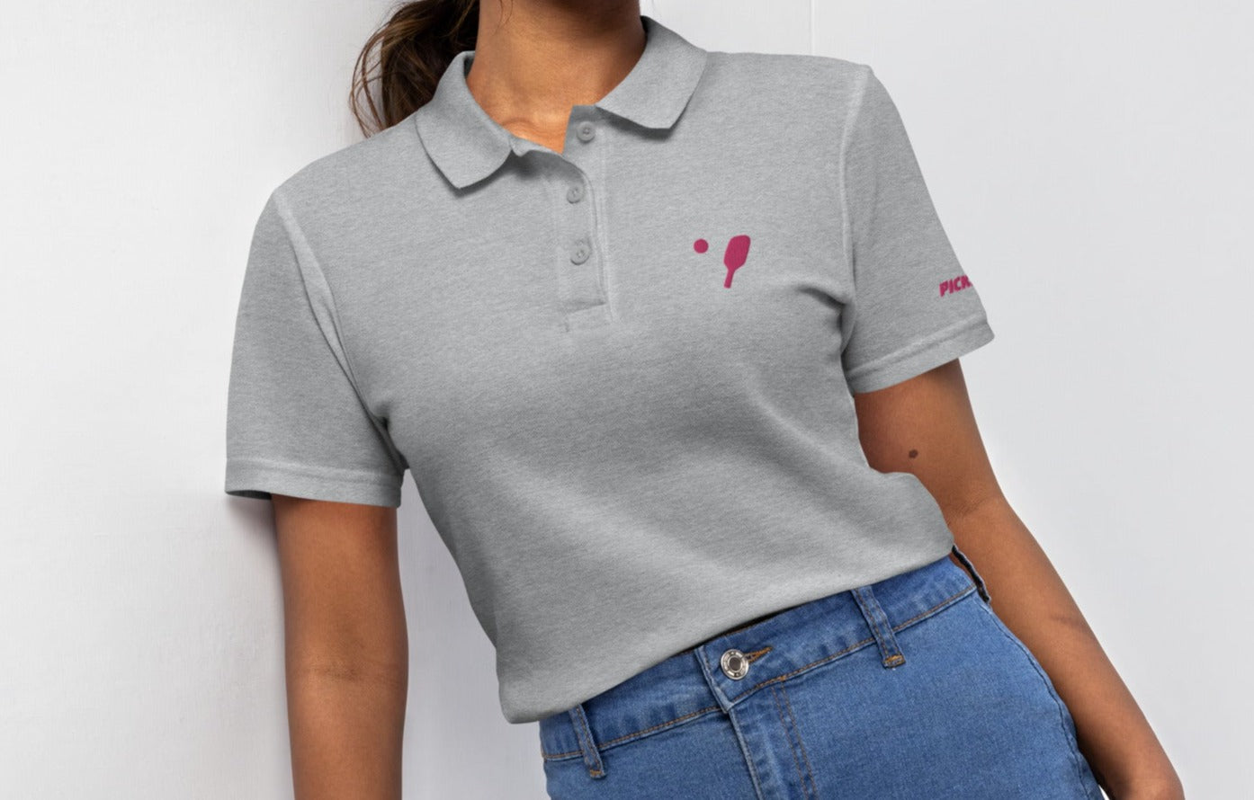 Casual grey women's pickleball polo shirt with subtle pink paddle and ball badge, perfect for pickleball enthusiasts looking for versatility both on and off the court.