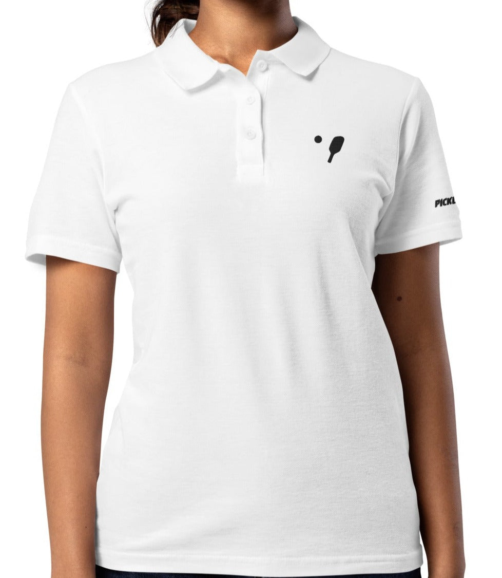 Model wearing a white women's pique polo shirt with subtle pickleball paddle embroidery on the left chest and black logo text on the right sleeve, designed by OOKAMI SPORTS