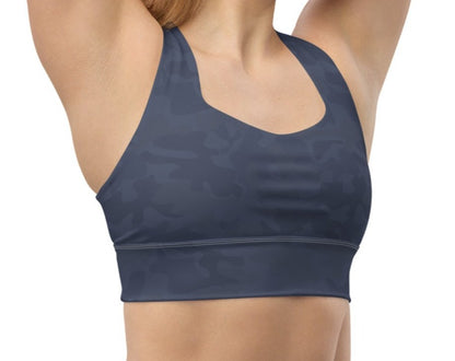 Front view of a woman wearing the Urban Gray Camo Pickleball Longline Sports Bra, showcasing a dark gray camouflage pattern, high neckline, and wide shoulder straps.