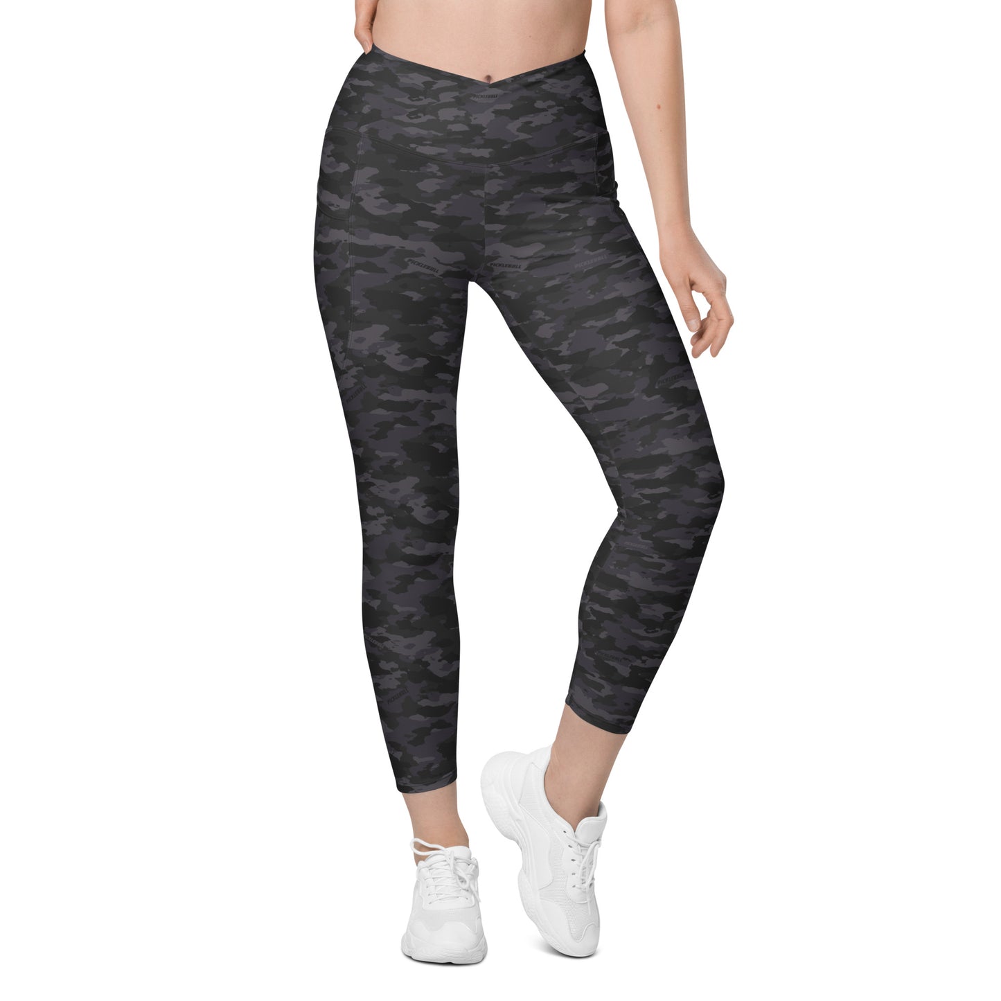  Woman wearing Stealth Camo Pickleball High-Waisted Crossover Leggings in a dark camouflage pattern, front view emphasizing the high-waisted, V-shaped crossover waistband and comfortable, ankle-length fit.
