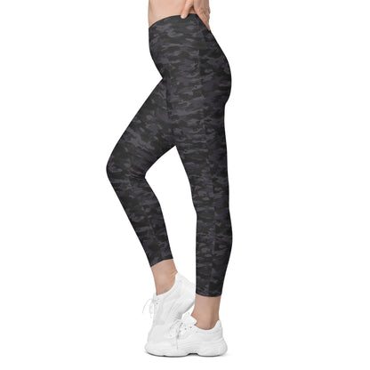 Woman wearing Stealth Camo Pickleball High-Waisted Crossover Leggings in a dark camouflage pattern, showcasing a left side view highlighting the sleek fit, high-waisted design, and side pocket.
