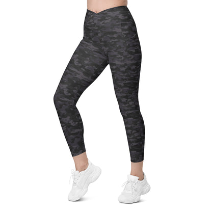Woman wearing Stealth Camo Pickleball High-Waisted Crossover Leggings in a dark camouflage pattern, showing a left side view with a high-waisted, V-shaped crossover waistband and ankle-length fit.