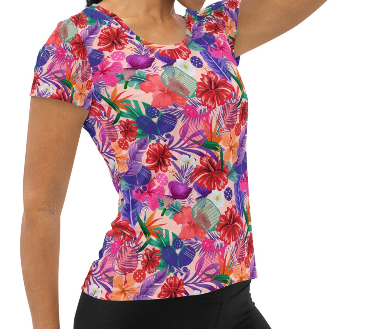 Woman wearing a vibrant Tropical Oasis Pickleball Performance Shirt, front view. Features bright floral and pickleball paddle design, perfect for sportswear and activewear enthusiasts on OOKAMI SPORTS.