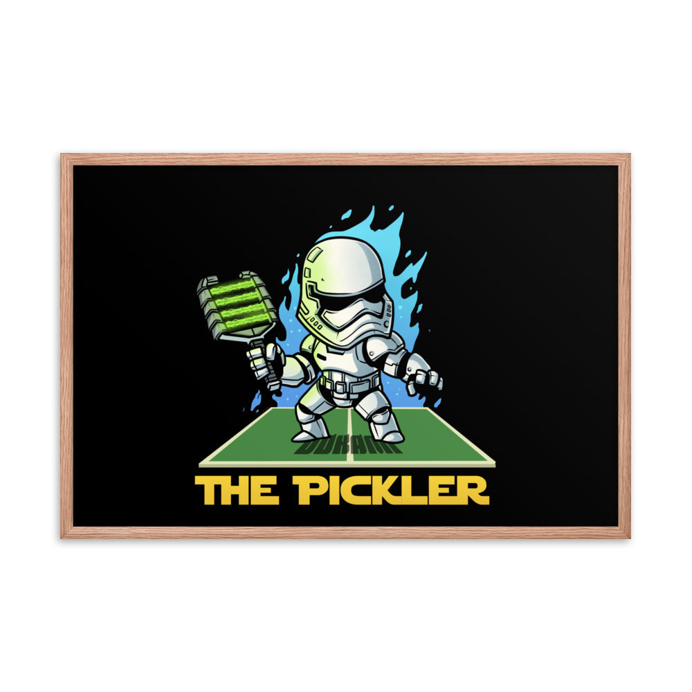 A large 24x36 framed poster in a red oak frame, featuring 'The Pickler', a playful Star Wars Stormtrooper-inspired character, holding a pickleball paddle on a pickleball court, set against a black background with dynamic blue flame-like details.