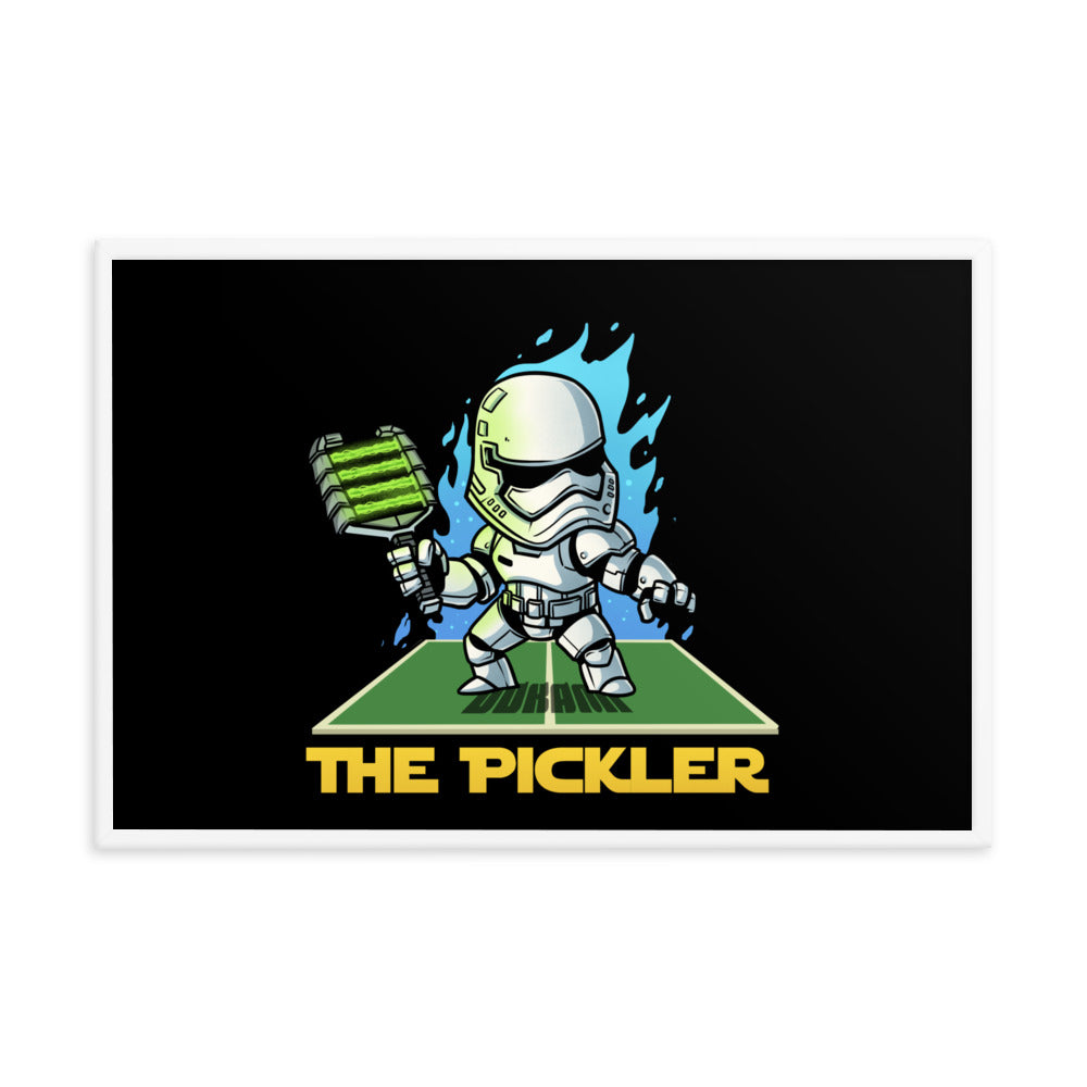  (24x36 inches): "A framed poster depicting a character styled like a stormtrooper, titled 'The Pickler'. The character wields a pickleball paddle in one hand, with blue flames and a dynamic stance on a green pickleball court. The frame is white.