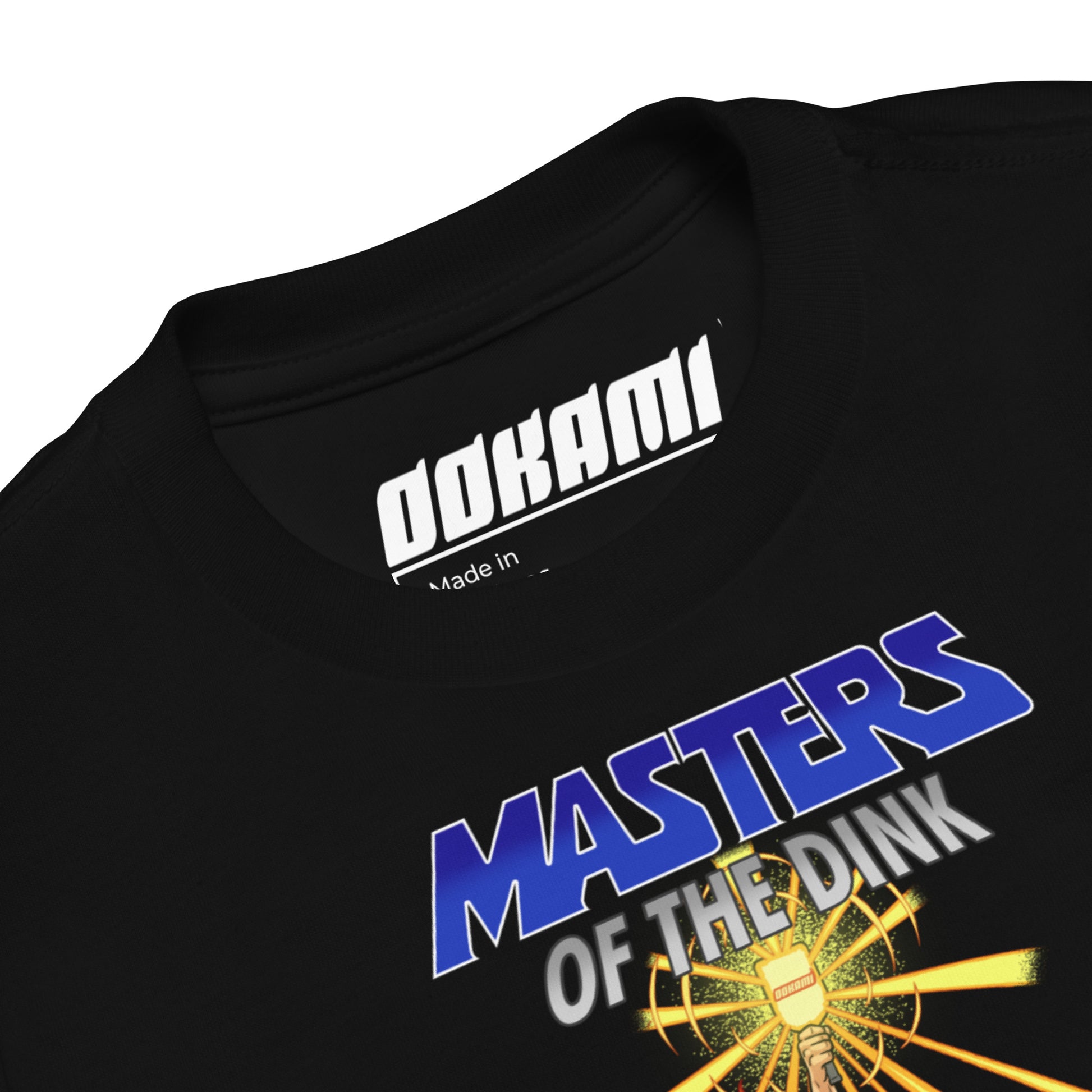 Close-up view of the collar and logo on the black 'Masters of the Dink' toddler t-shirt by OOKAMI.