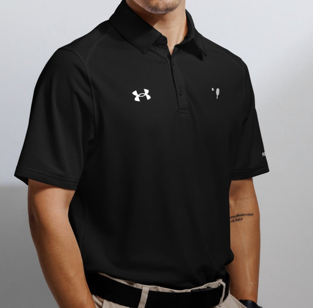 Close-up of a man wearing a black Under Armour® polo shirt featuring the Under Armour logo on the left chest and the OOKAMI SPORTS pickleball symbol on the right chest, designed for optimal performance and comfort.