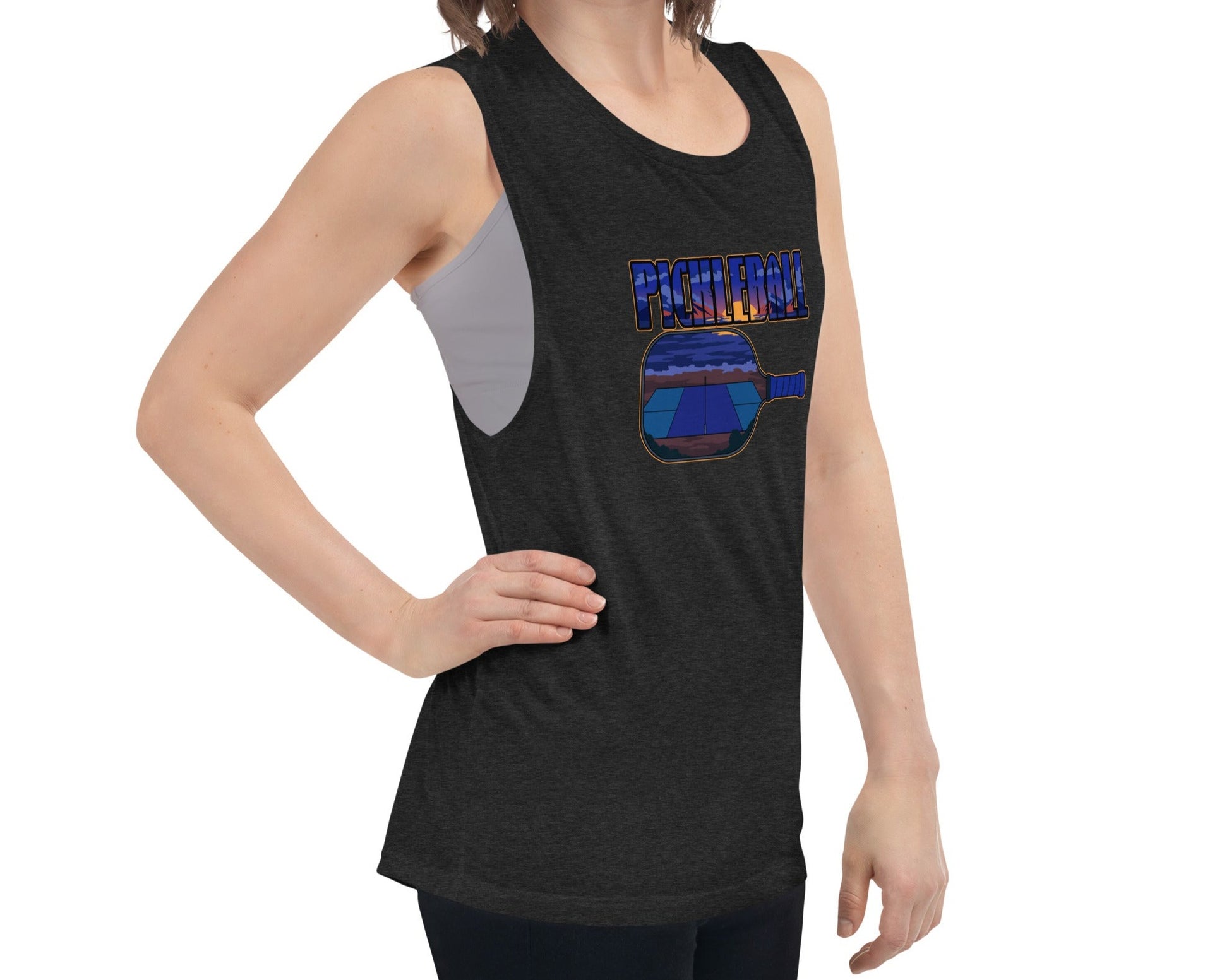 Woman wearing a black heather muscle tank with a pickleball sunset design, front view.