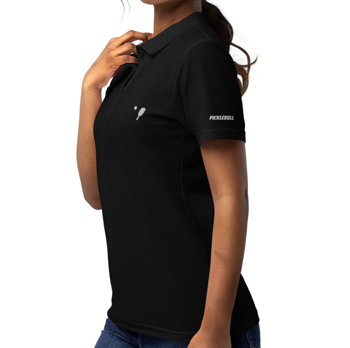 Woman posing with a hand on her hip, wearing a black OOKAMI SPORTS Women’s Pique Pickleball Polo Shirt, featuring a white pickleball logo on the chest.