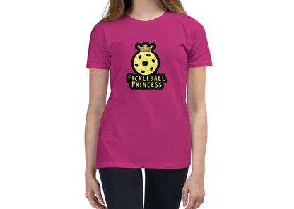 Front view of a pink youth t-shirt worn by a model, featuring a yellow pickleball with a crown and the text "Pickleball Princess.